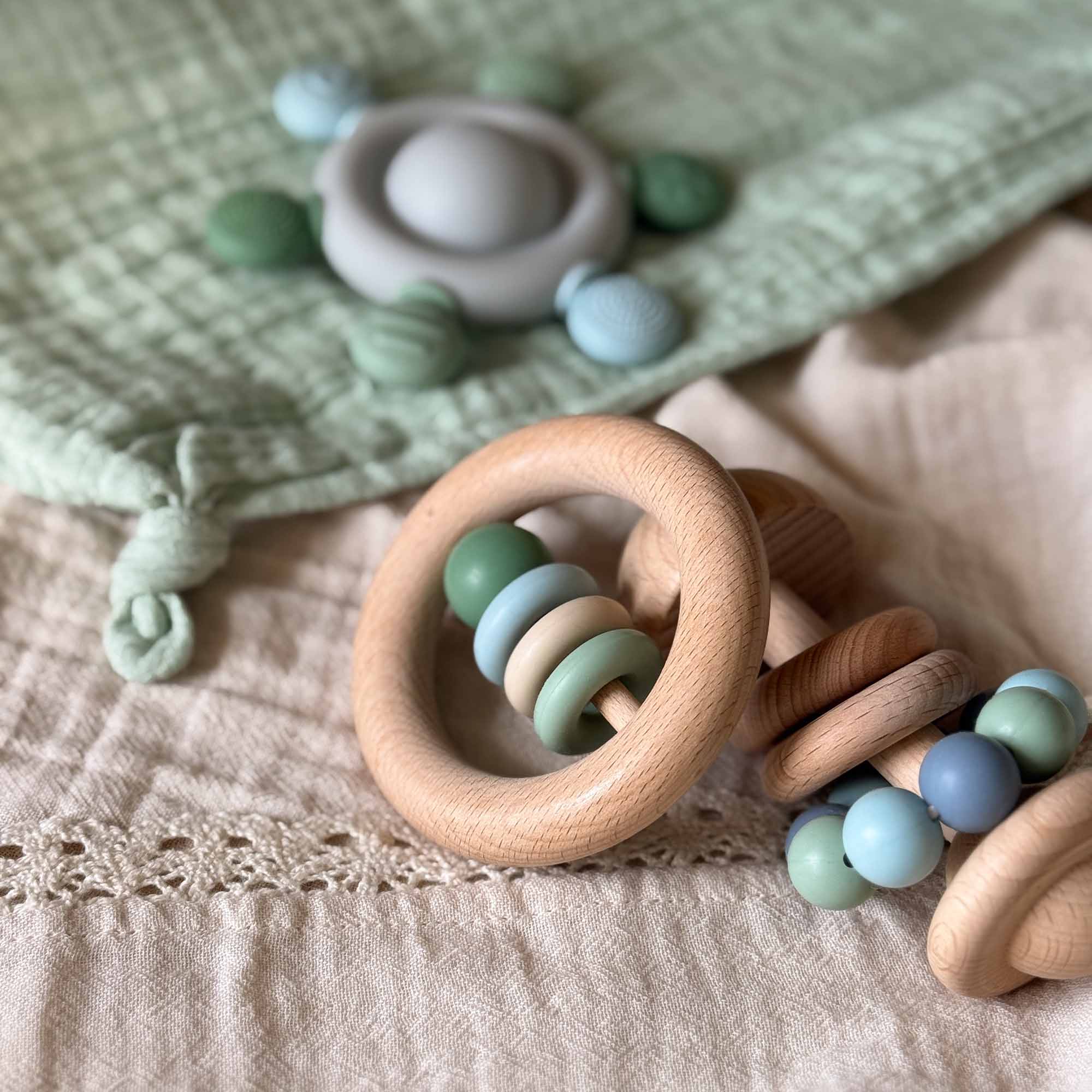 En tre babyrangle med pastellgrønne og blå silikonperler ringrangle grønn