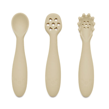 Nybegynnerskjeer i silikon i beige med glatt design og unike utskjæringer på håndtakene, sett med tre deler