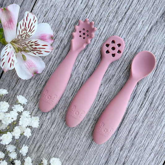 Set med tre rosa silikon nybegynnerskjeer med blomsterhoder og preget logo for babyttingesting