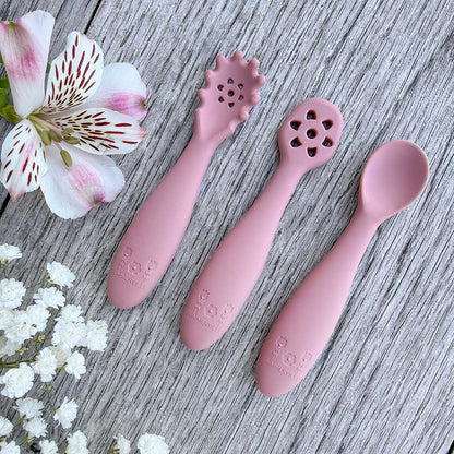 Set med tre rosa silikon nybegynnerskjeer med blomsterhoder og preget logo for babyttingesting