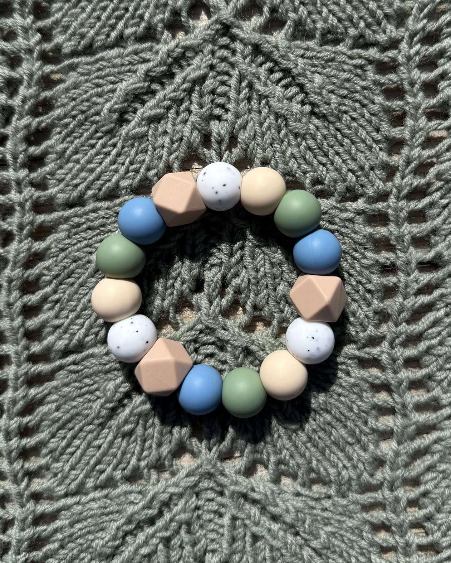 Pastellfarget håndlaget bitering i bpa fri silikon med runde og geometriske perler i blått, grønt, beige og hvitt som lindrer ømme gommer
