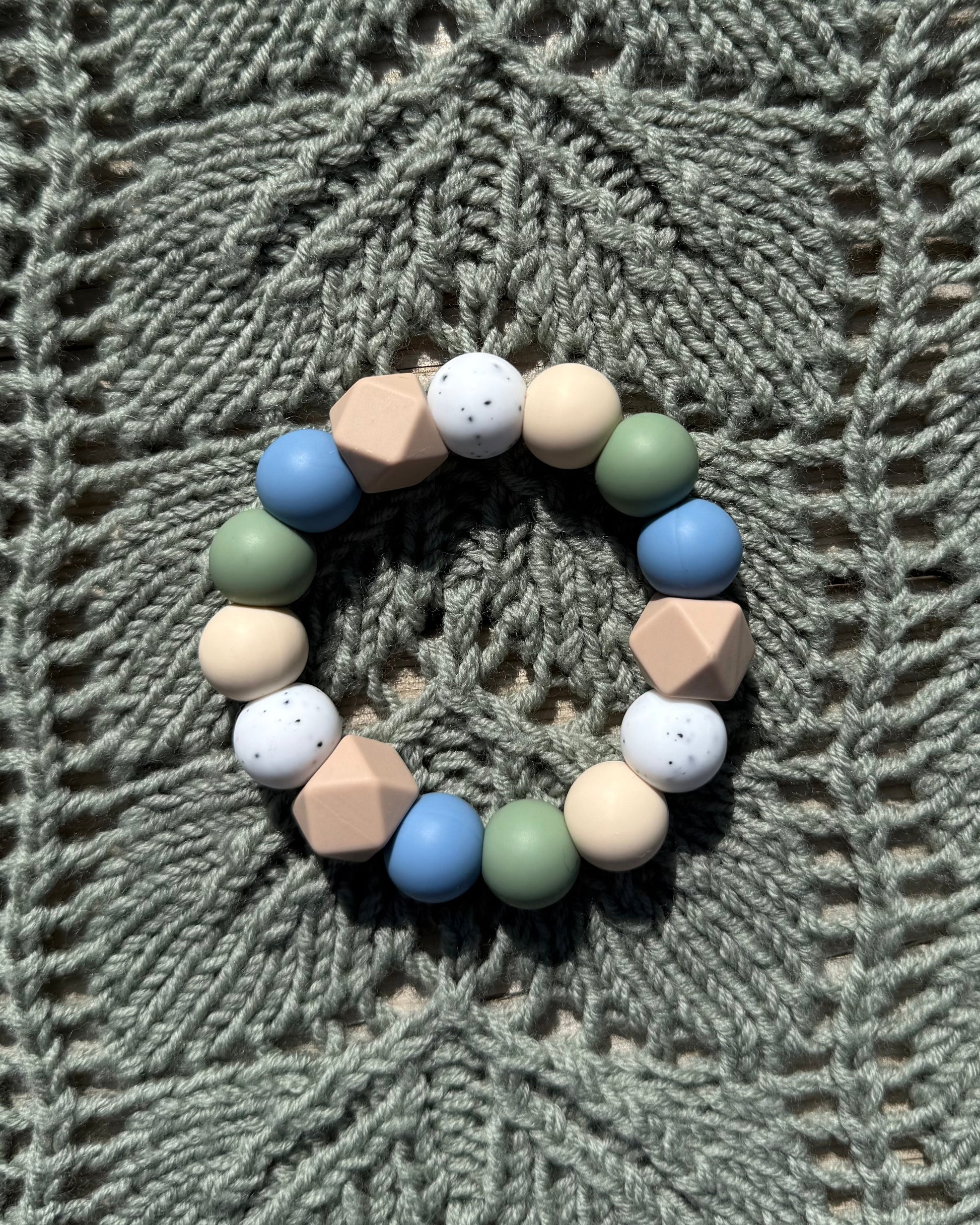 Pastellfarget håndlaget bitering i bpa fri silikon med runde og geometriske perler i blått, grønt, beige og hvitt som lindrer ømme gommer