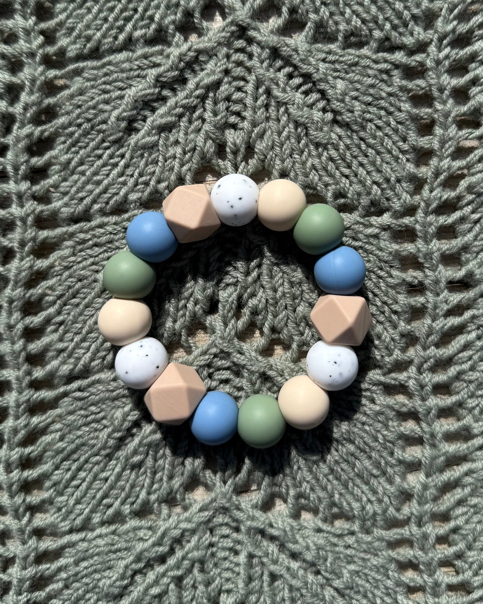 Pastellfarget håndlaget bitering i bpa fri silikon med runde og geometriske perler i blått, grønt, beige og hvitt som lindrer ømme gommer