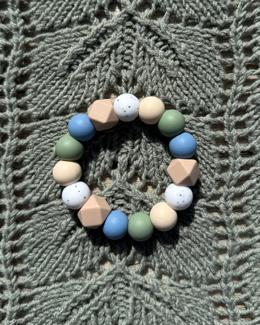 Pastellfarget håndlaget bitering i bpa fri silikon med runde og geometriske perler i blått, grønt, beige og hvitt som lindrer ømme gommer