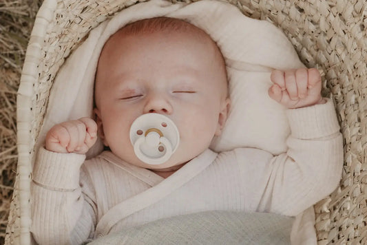En myk hvit pacifier med rund, glatt design og subtile gullfargede detaljer i babyens munn for multifunksjonell babyklut musselinkluter 70x70 2pk ivory