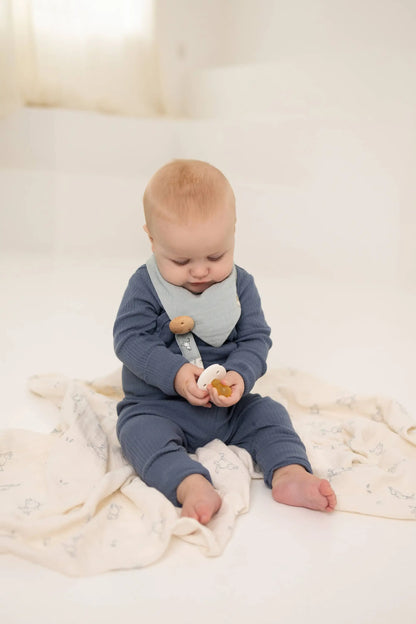 Baby i marineblå ribbestrikket body med lys grå smekke med trekknapper holder smokken med praktisk klips i økologisk bomull