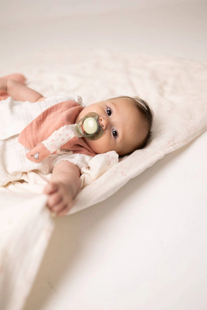 A baby wearing a rosa moomin smokkelenke in økologisk bomull with praktisk klips holder smokken på plass