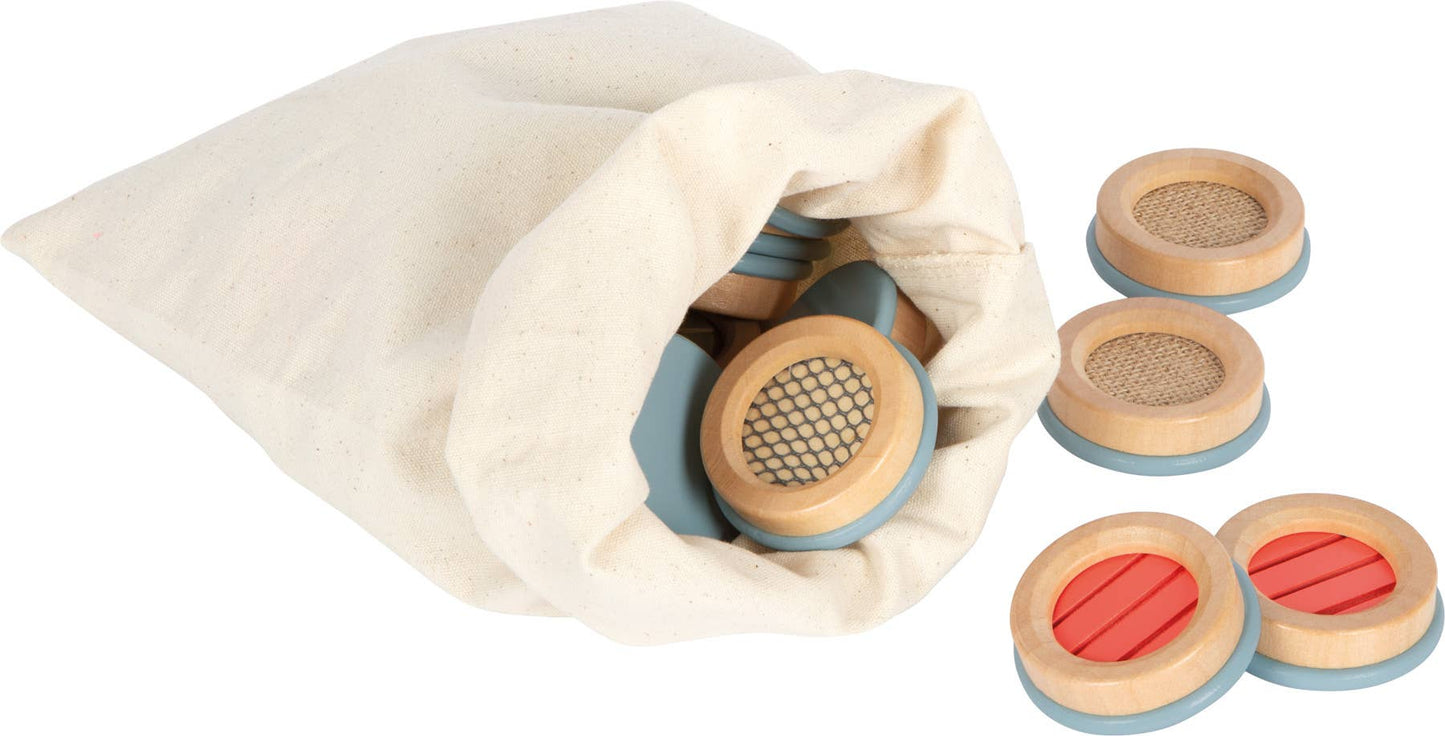 Wooden circular sound blocks with light blue bases and textured natural wood, red, and beige tops in sensorisk memo medfølgende bomullsposen