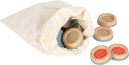 Wooden circular sound blocks with light blue bases and textured natural wood, red, and beige tops in sensorisk memo medfølgende bomullsposen